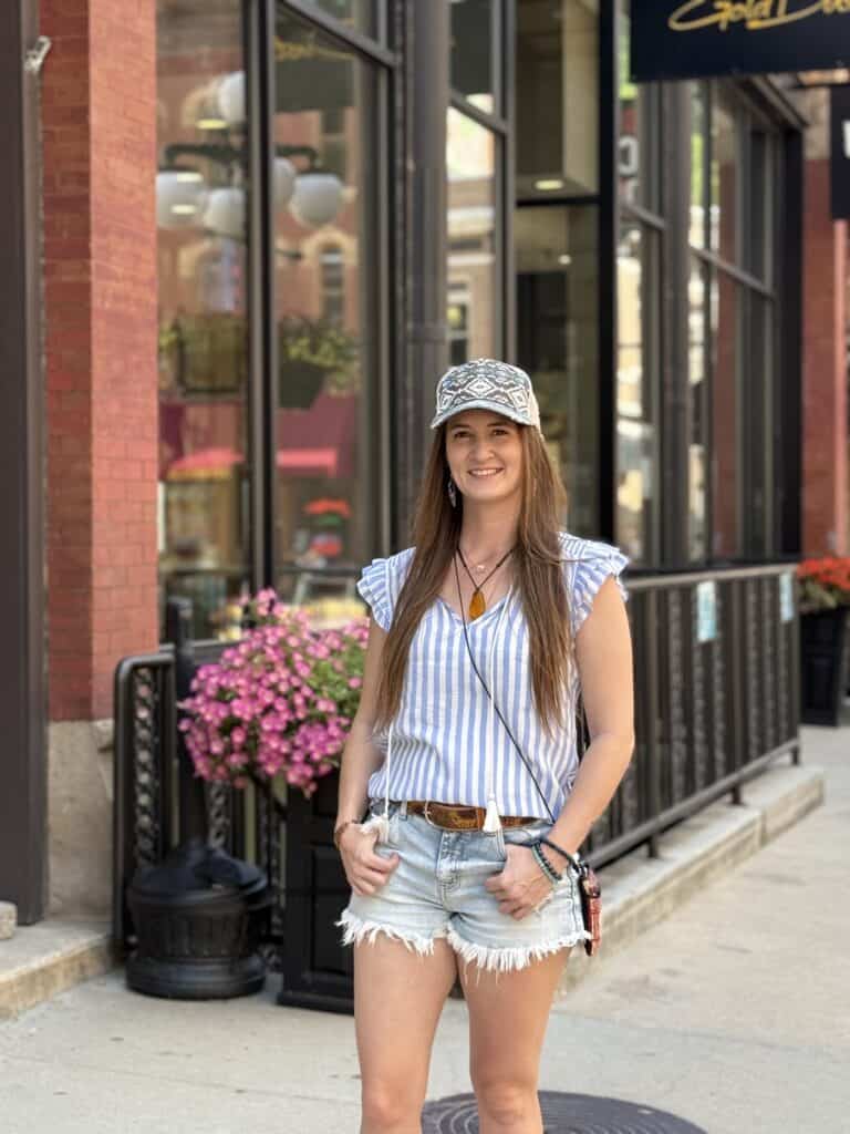 Woman smiling in casual summer outfit outside a storefront.