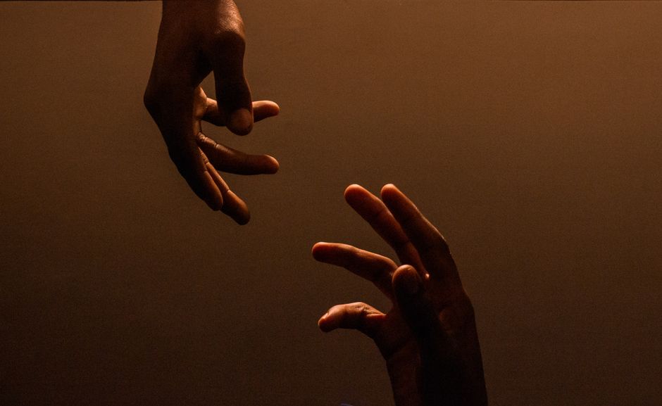 pexels-photo-31726301-31726301 Two hands reaching towards each other against a dark, warm background, symbolizing energetic cord connection and how to cut energetic cords.